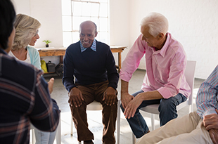 A group of seniors talks while seated around a circle.