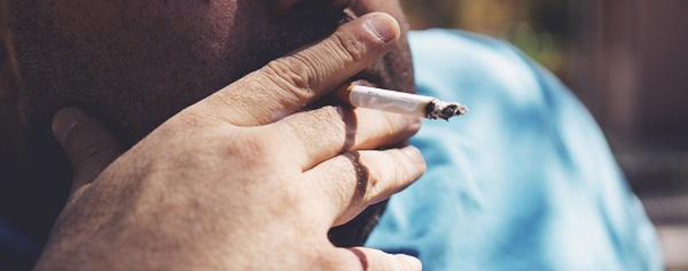 A man holds a lit cigarette