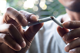 A man breaks a cigarette in half.