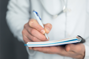 A close up of a doctor holding a notebook.