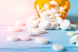 A bottle of opioids spills out onto a table.