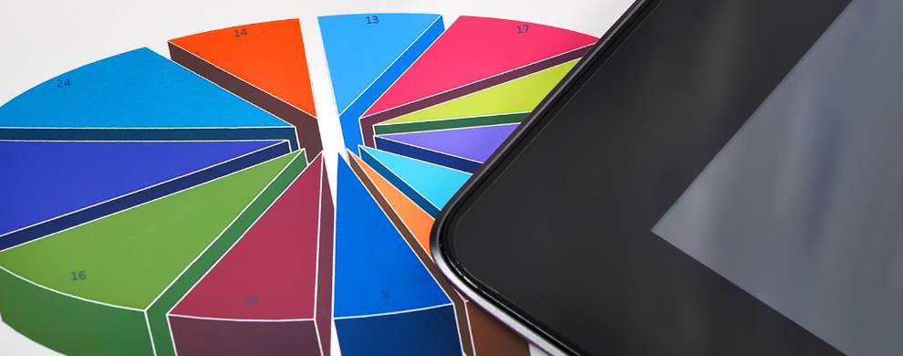 A tablet lays on top of a colorful pie chart.